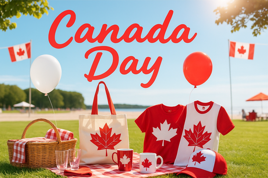 Canada Day picnic setup with custom red and white gifts including tote bag, t-shirts, mugs, and cap featuring maple leaf designs, with balloons, Canadian flags, and a wicker basket on a grassy park near the beach.