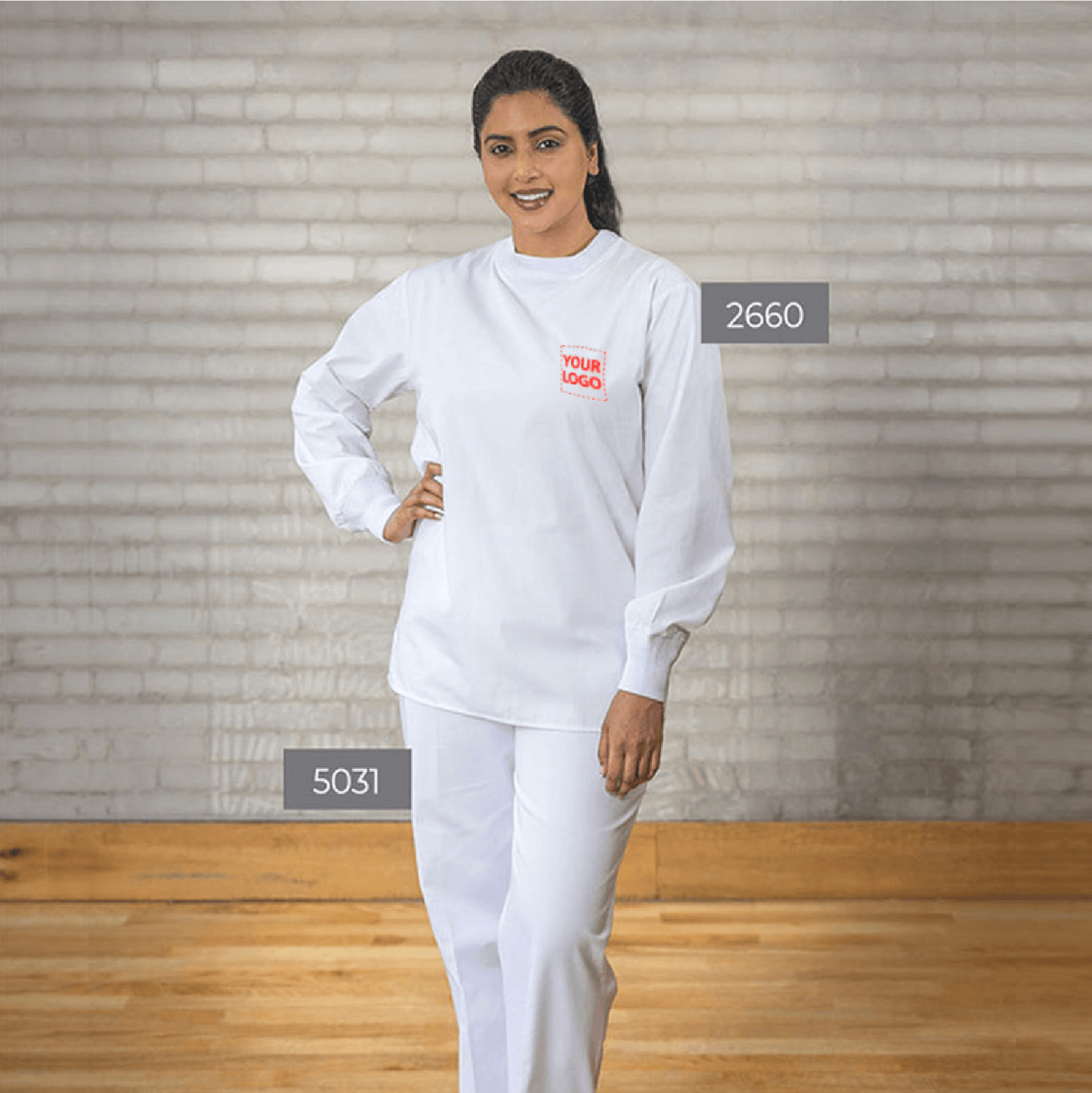 Woman wearing a white crew-neck scrub set with embroidered logo, featuring long sleeves and straight-leg pants