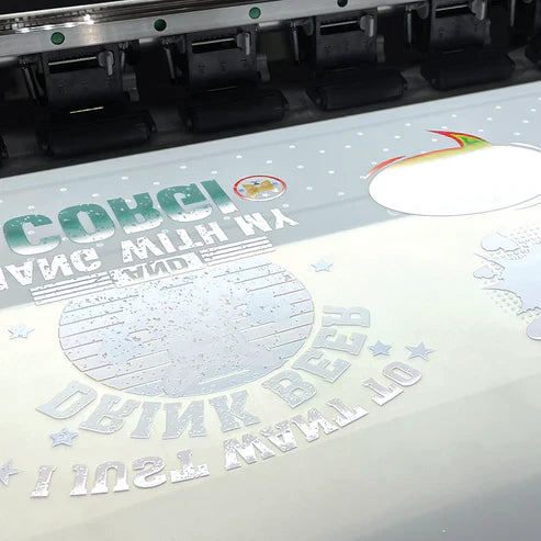 Custom DTF (Direct to Film) heat transfer printing process showing vibrant and white ink designs on a transfer sheet ready for garment application