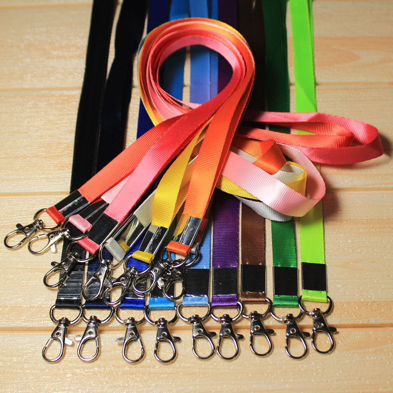 Assorted custom nylon lanyards in various colors with metal lobster clips, displayed on wooden background, ideal for ID badges and promotional events