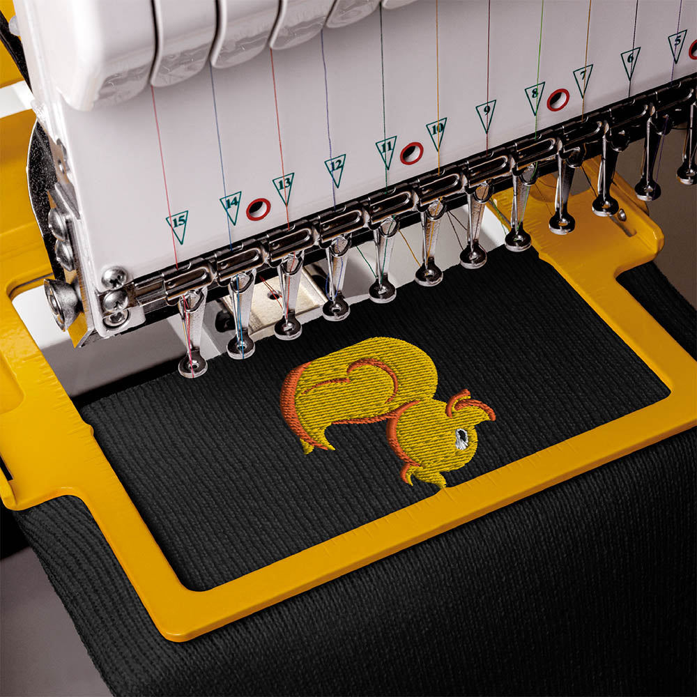 Embroidery machine stitching a yellow duck logo onto black fabric, showing close-up detail of the needlework process.