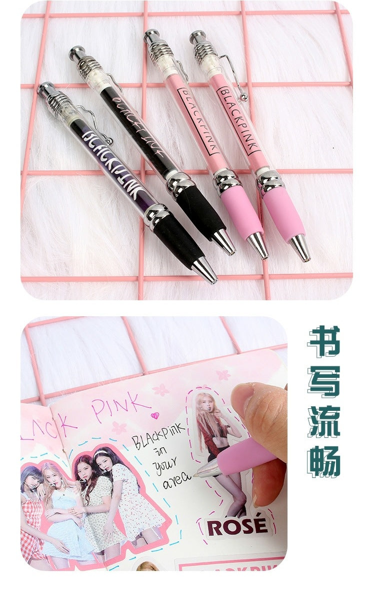 Pull-out ad ballpoint pens with Blackpink branding, pink and black grips, shown writing on themed stationery.