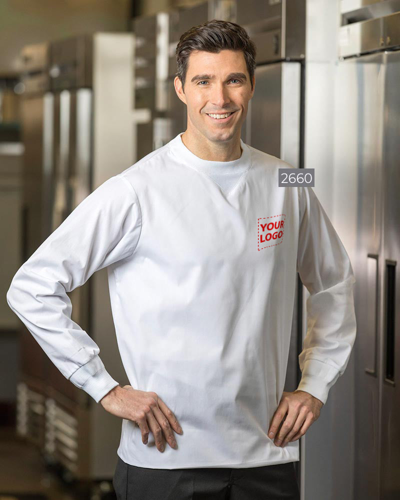 Man wearing a white crew-neck scrub top with embroidered logo, long sleeves, and elastic cuffs, standing in a professional setting